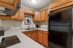 Eine Küche mit Holzausstattung, einem schwarzen Kühlschrank, einer Spüle und einer Kaffeemaschine.