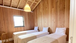 Une pièce de cabane en bois avec deux lits, une fenêtre et une échelle en bois.