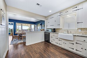 A kitchen with white cabinets, a built-in microwave, and a large window.