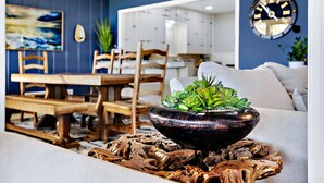 Uma sala de estar moderna com uma mesa de jantar de madeira, cadeiras, um sofá e uma tigela decorativa com plantas.