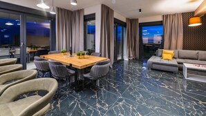 A modern living room with a wooden dining table, grey upholstered chairs, a grey sofa, and a patterned floor. - Villa Luna- Private Heated Pool (Novalja)