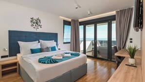 A modern hotel room with a large bed, a desk, a potted plant, and a balcony with a view. - Villa Luna- Private Heated Pool (Novalja)