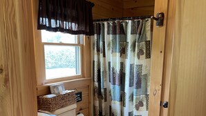 Ein Badezimmer einer Holzhütte mit Toilette, Waschbecken und Fenster.