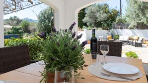 Une table à manger ornée d’un vase de lavande, d’une bouteille de vin et d’un verre.