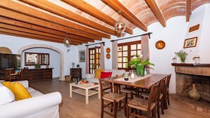 Un salon spacieux avec un plafond en bois, un coin repas avec une table et des chaises, et une cheminée.