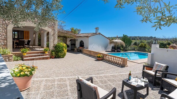 Un espace patio aménagé avec du mobilier d’extérieur, une piscine et un mur en pierre.