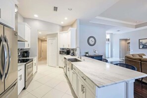 A modern kitchen with a marble countertop, stainless steel appliances, and white cabinetry.