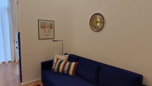 Ein Wohnzimmer mit einem blauen Sofa, einem gemusterten Teppich und einer dekorativen Platte an der Wand.