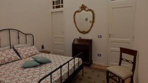 Ein Schlafzimmer mit Bett, Stuhl, Spiegel und einer Tür.