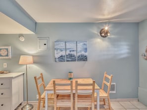 A dining area with a wooden table and chairs, a wall-mounted lamp, and a ceiling light fixture.
