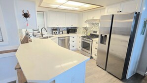 Una cocina moderna con armarios blancos, electrodomésticos de acero inoxidable y una isla curva.
