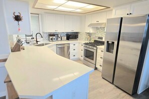 Una cocina moderna con gabinetes blancos, electrodomésticos de acero inoxidable y una isla grande.