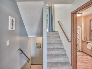 Un escalier avec une rampe, un interrupteur fixé au mur et un tableau encadré.