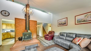 A living room with a fireplace, leather sofa, and a checkered rug. - Wisconsin Vacation Rental Retreat w/ Deck (Twin Lakes)