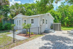 A small, single-story house with a fenced yard, a paved driveway, and a small garden area. - Pet-Friendly Cottage Near Beach: King Bed/Fire Pit (Bonita Springs)