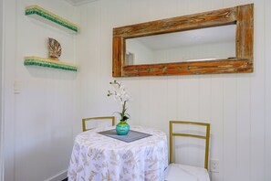 Um quarto com uma mesa, cadeiras, um vaso de flores, um espelho e prateleiras decorativas.