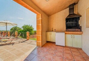 An outdoor kitchen area with a grill, a refrigerator, and a dining table with chairs. - Country house with 5 bedrooms with barbecue and private pool (Son Carrió)