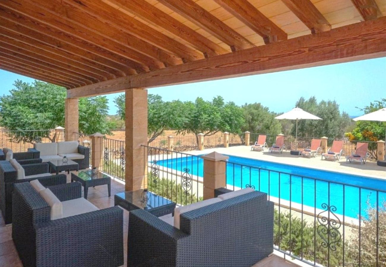 A covered outdoor area with wicker furniture and a view of a swimming pool.