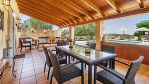 An outdoor patio with wicker furniture, a glass table, and a pool in the background. - 3 bedroom country house with private pool and barbecue (Son Macià)
