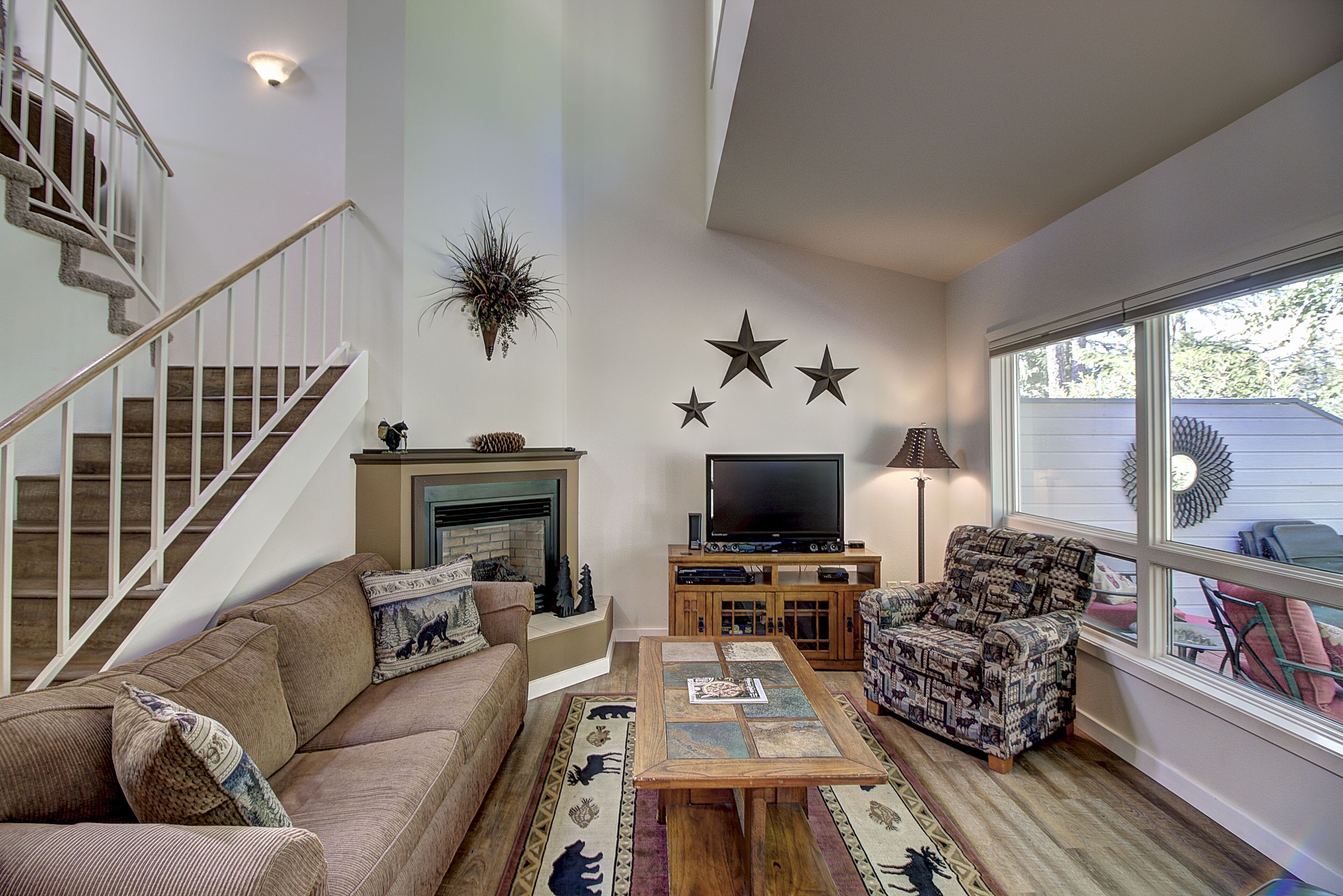 A living room with a staircase, a fireplace, a television, and a patterned armchair.