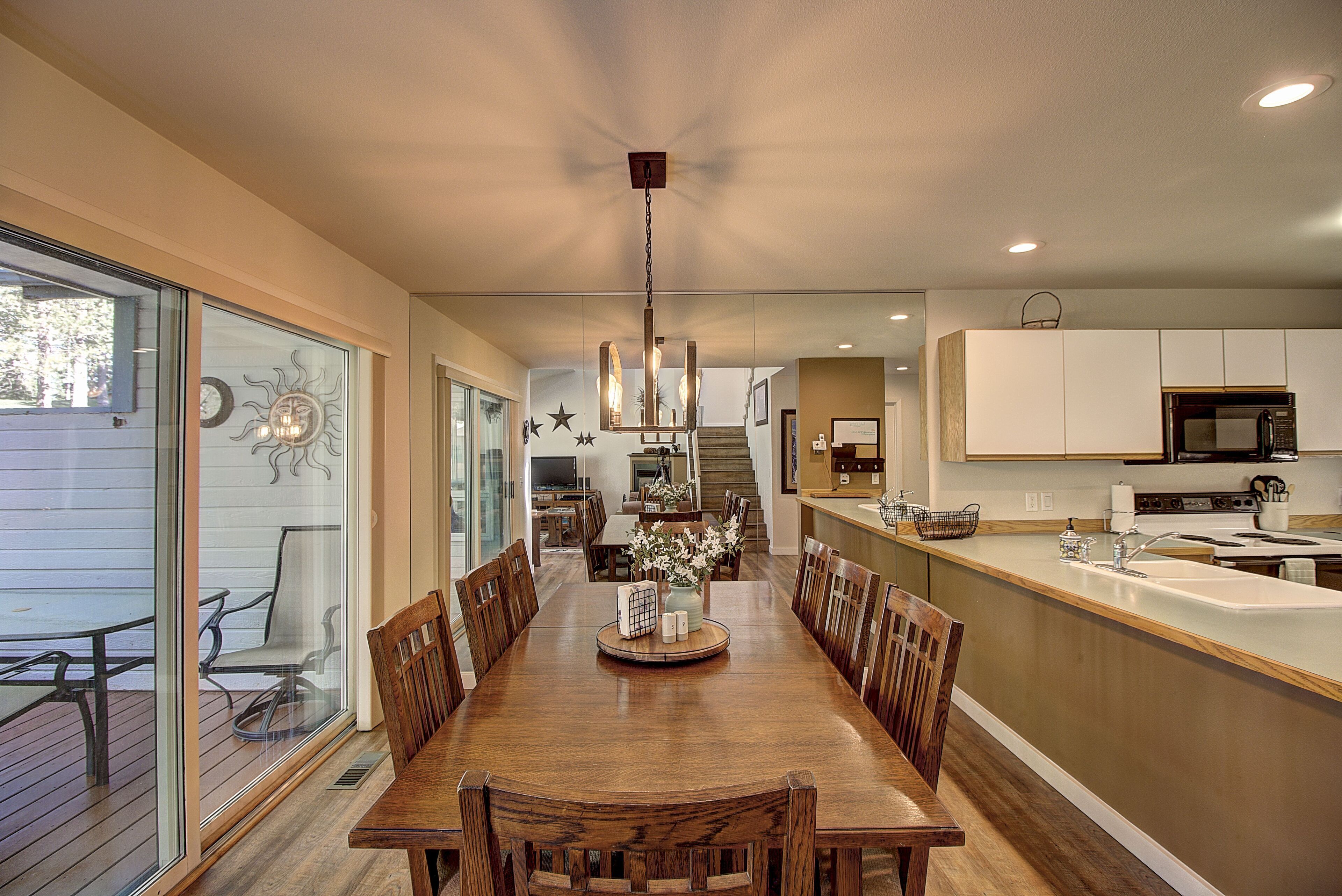 A modern kitchen with a wooden dining table, white cabinets, and a built-in island with a sink.