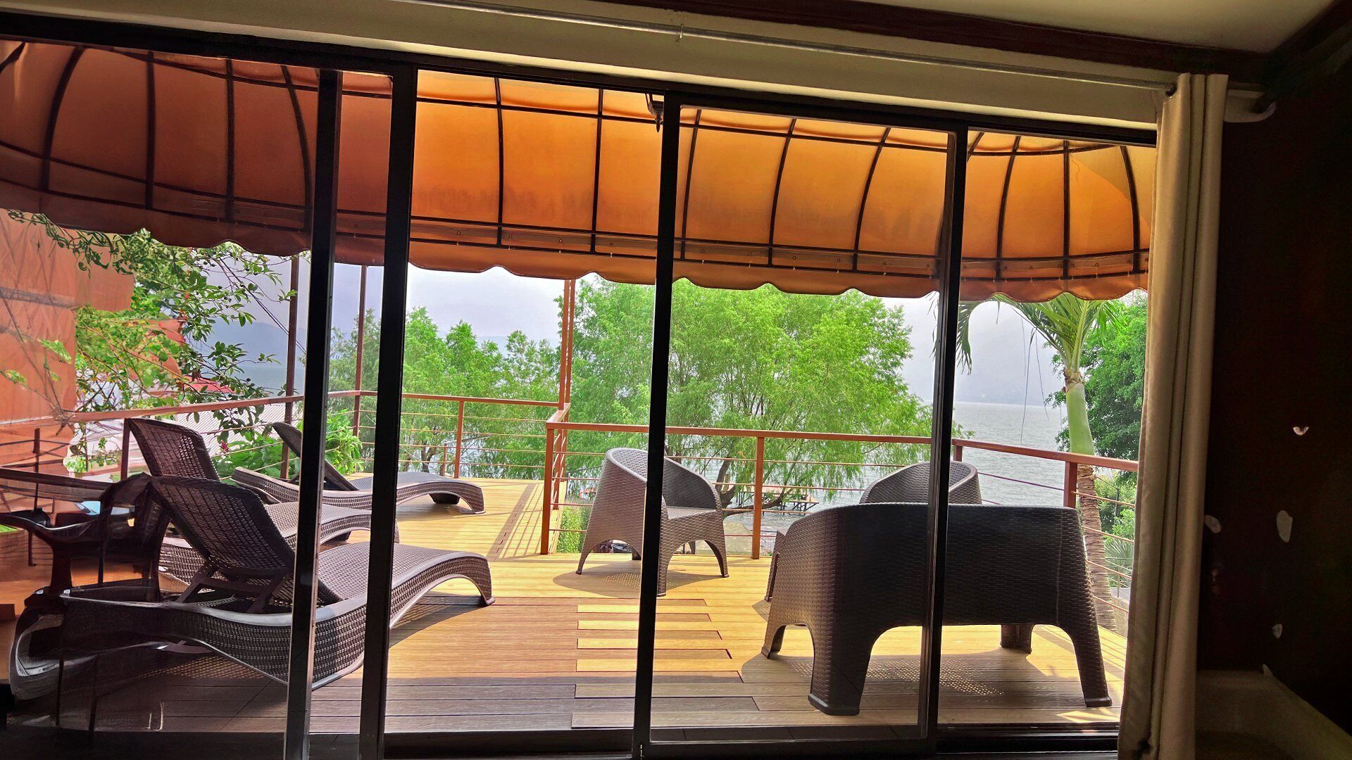 A covered outdoor deck with wicker furniture and a view of the sea.