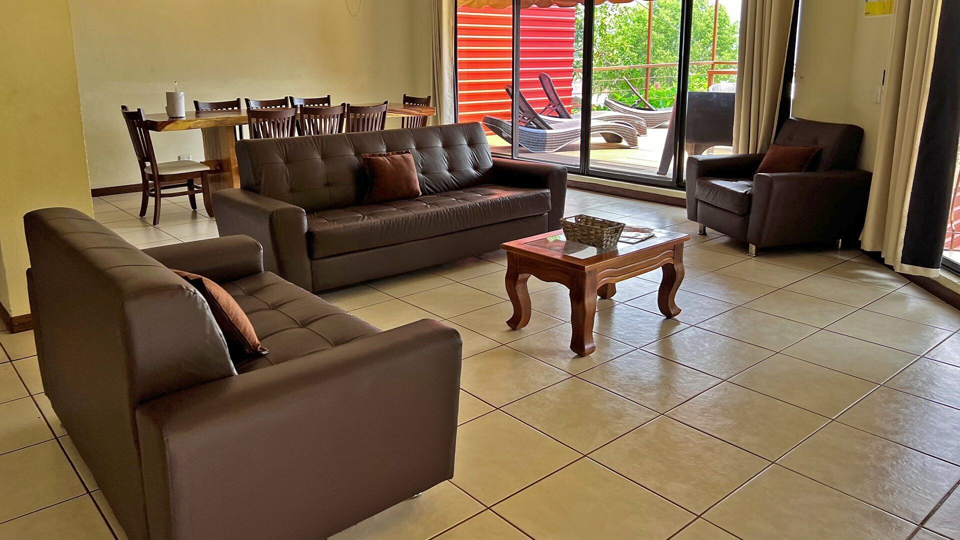 A living room with a sofa, a coffee table, and a dining area with chairs and a table.