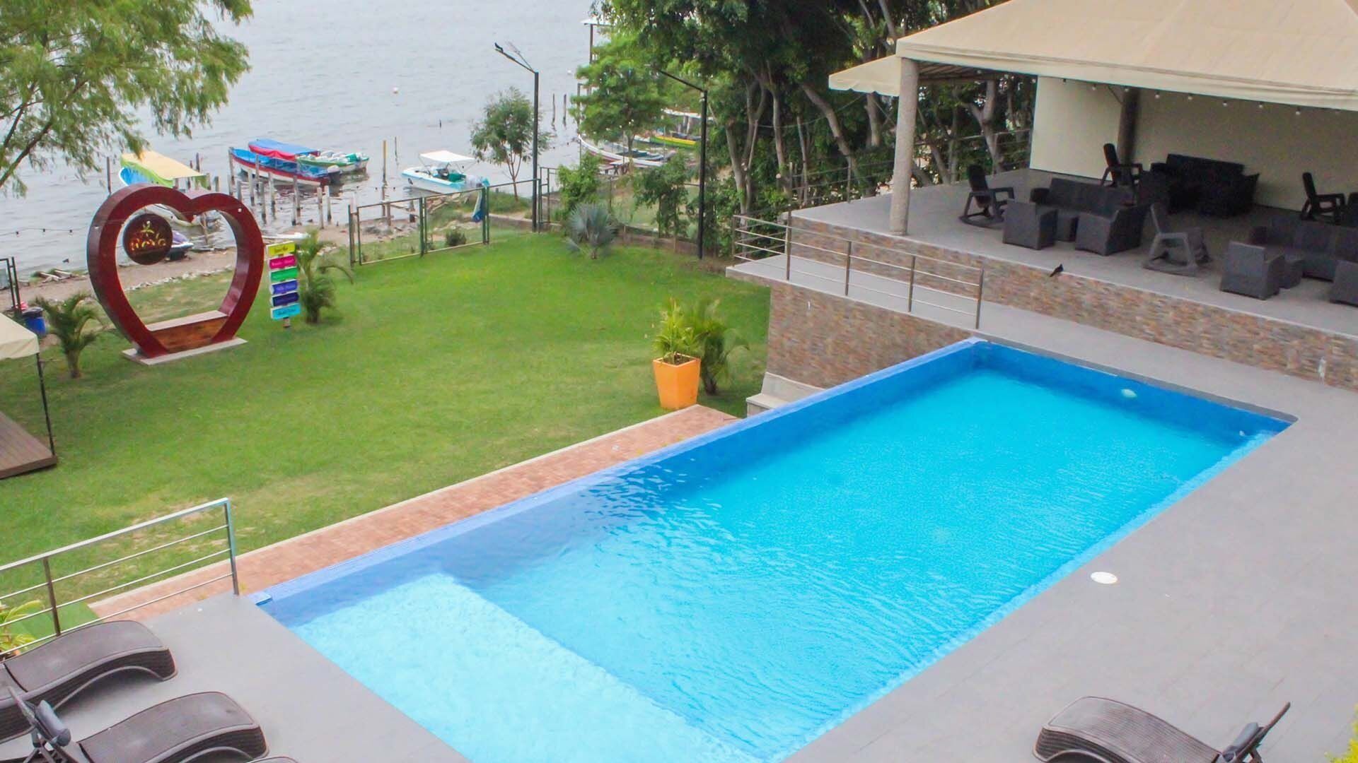 Ein Pool mit Meerblick, einer herzförmigen Skulptur und Sitzgelegenheiten im Freien.