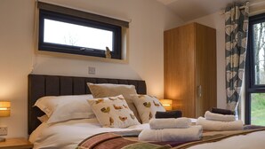 Ein ordentlich gemachtes Bett mit Kissen, ein Nachttisch mit Lampe, ein Fenster mit Blick und ein Kleiderschrank.