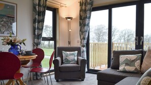 Ein Zimmer mit Esstisch, Stühlen, einer Couch und Blick ins Freie.