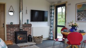 Ein gemütliches Wohnzimmer mit Kamin, Fernseher und Essbereich mit roten Stühlen.