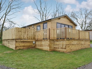 A wooden cabin with a deck, large windows, and a fenced area. - 1 bedroom accommodation in Brocklebank, near Caldbeck and Uldale (Brocklebank, near Caldbeck and Uldale)