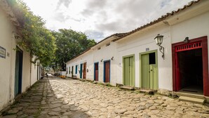 A cobblestone street lined with white buildings featuring colorful doors. - Ferraria Guest House (Paraty)