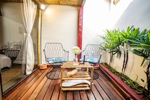 A wooden deck with two wicker chairs, a small table, and a potted plant. - Ferraria Guest House (Paraty)