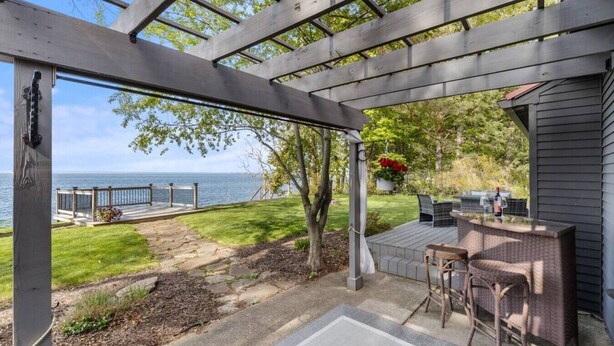A covered patio with a view of the sea, outdoor furniture, and a small garden area. - Lake Ontario Beauty! Sleeps 4! (Williamson)