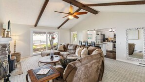 A spacious living room with a sectional sofa, a round coffee table, and a fireplace. There is a kitchen in the background with modern appliances. - Lake Ontario Beauty! Sleeps 4! (Williamson)