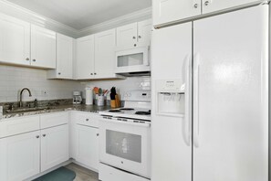 A modern kitchen with white cabinetry, a built-in microwave, a stove, and a refrigerator.