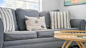 Ein graues Sofa mit gestreiften Kissen und ein Holzstuhl davor.