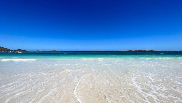 Une plage à l’eau turquoise et au sable blanc.