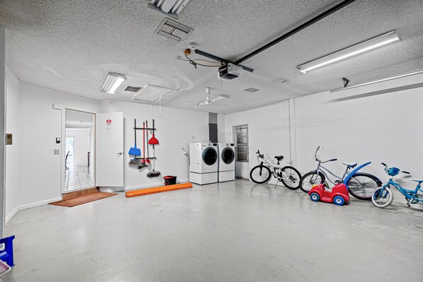 A clean, modern laundry room with a washing machine, dryer, ceiling fan, and bicycles.