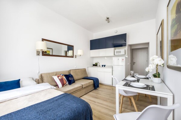 Une chambre d’hôtel moderne équipée d’un lit, d’un canapé, d’une table à manger avec des chaises, d’un four à micro-ondes et d’un petit coin cuisine.