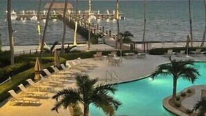 A resort pool area with lounge chairs and palm trees, overlooking the ocean. - This condo is located in one of Islamorada's most prestigious condo complexes. (Islamorada)