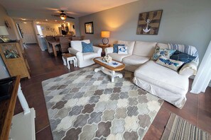 Un salon comprenant un canapé, des fauteuils, une table basse et un tapis à motifs.