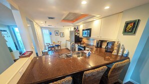 Una cocina con una isla central, sillas, una mesa de comedor y un televisor.