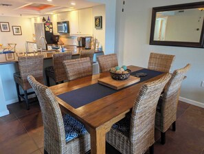 Un espace repas avec une table en bois, des chaises en osier et un grand saladier au centre.