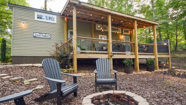 Une terrasse en bois avec des fauteuils Adirondack et un foyer extérieur.