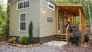Une petite cabane à un seul étage, dotée d’un porche et d’une pancarte accueillante.