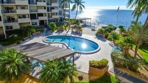 A resort with a swimming pool, palm trees, and a view of the ocean.