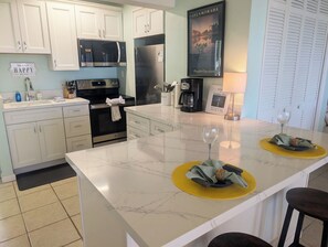 A modern kitchen with white cabinets, a stainless steel refrigerator, a microwave, and a coffee maker.
