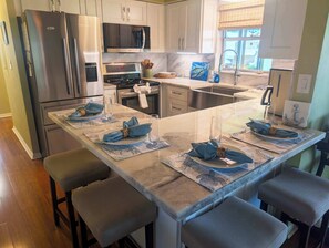 A modern kitchen with stainless steel appliances, a central island with seating, and a view of the outdoors.